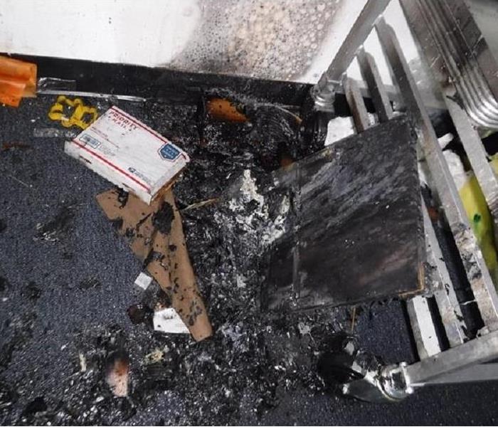 A piece of the ceiling with fire debris around it leaning on a stainless steel cart.