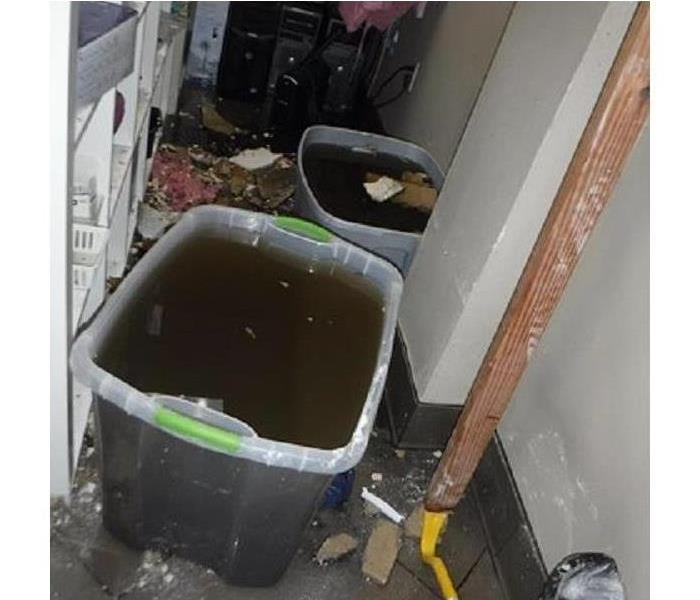 Two plastic tubs filled with black water sitting in a hallway.