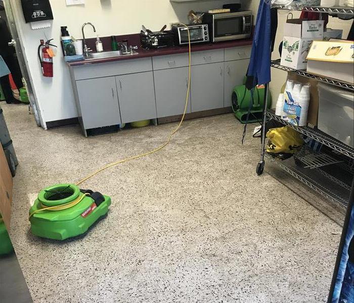 Green air movers drying puddles of water in an office.